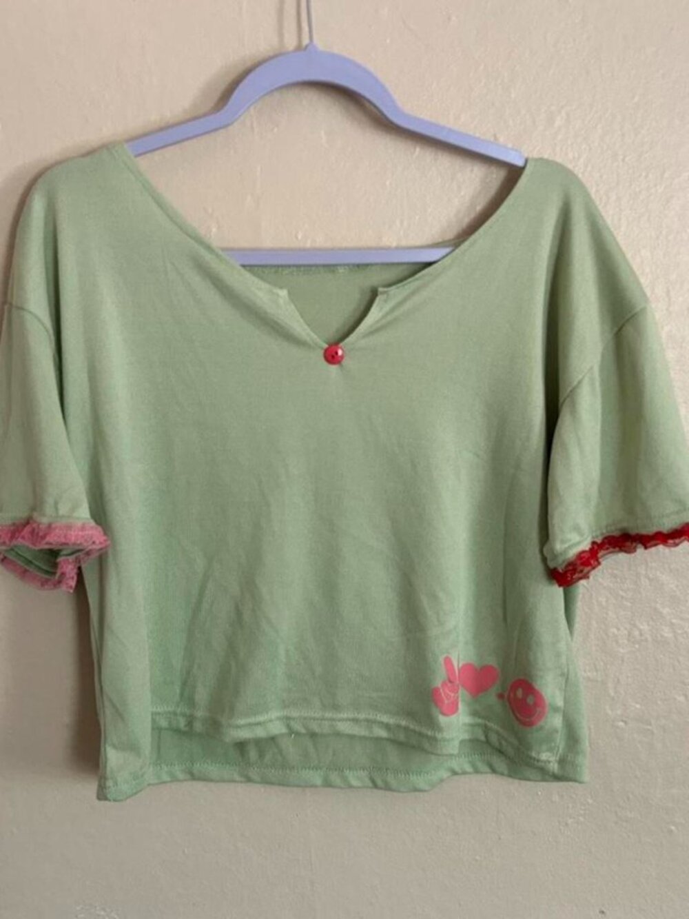 Mint green cropped top with playful red/pink details, a vintage button neckline
